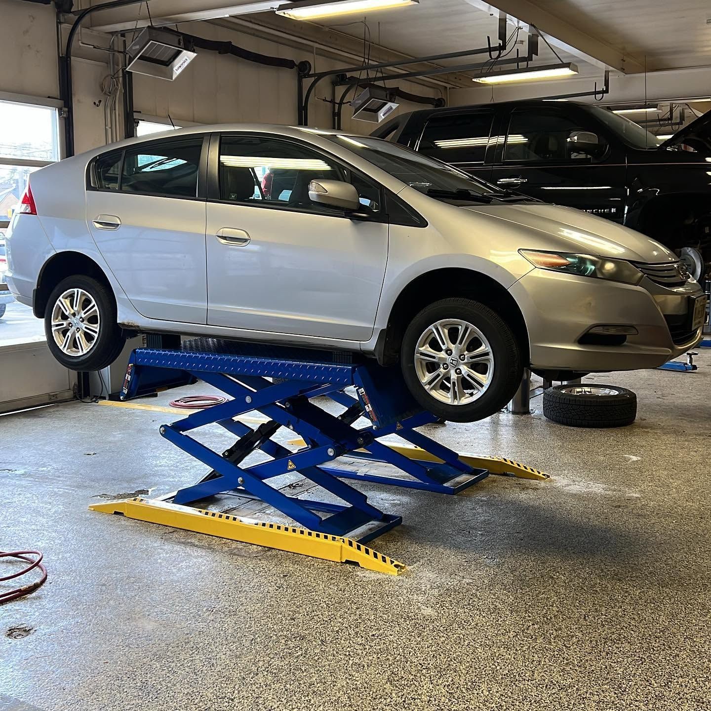Silver sedan lifted on a blue scissor lift in an auto repair shop garage | Lacey Auto Care
