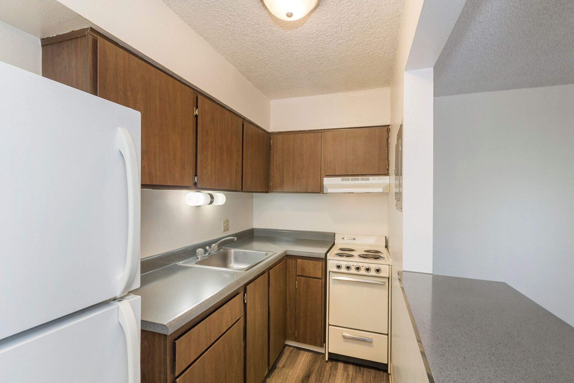 Small kitchen with brown cabinets, white appliances, and a gray countertop.
