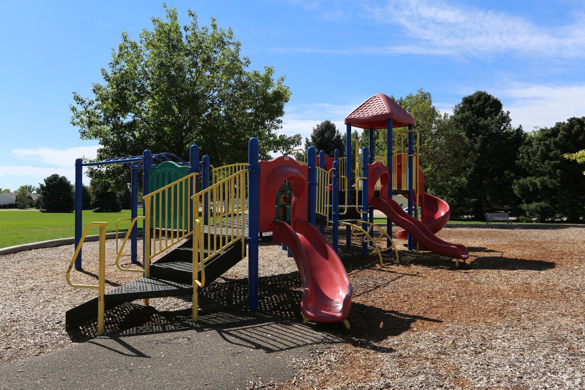 Playground with red slides, yellow stairs, and blue sky.