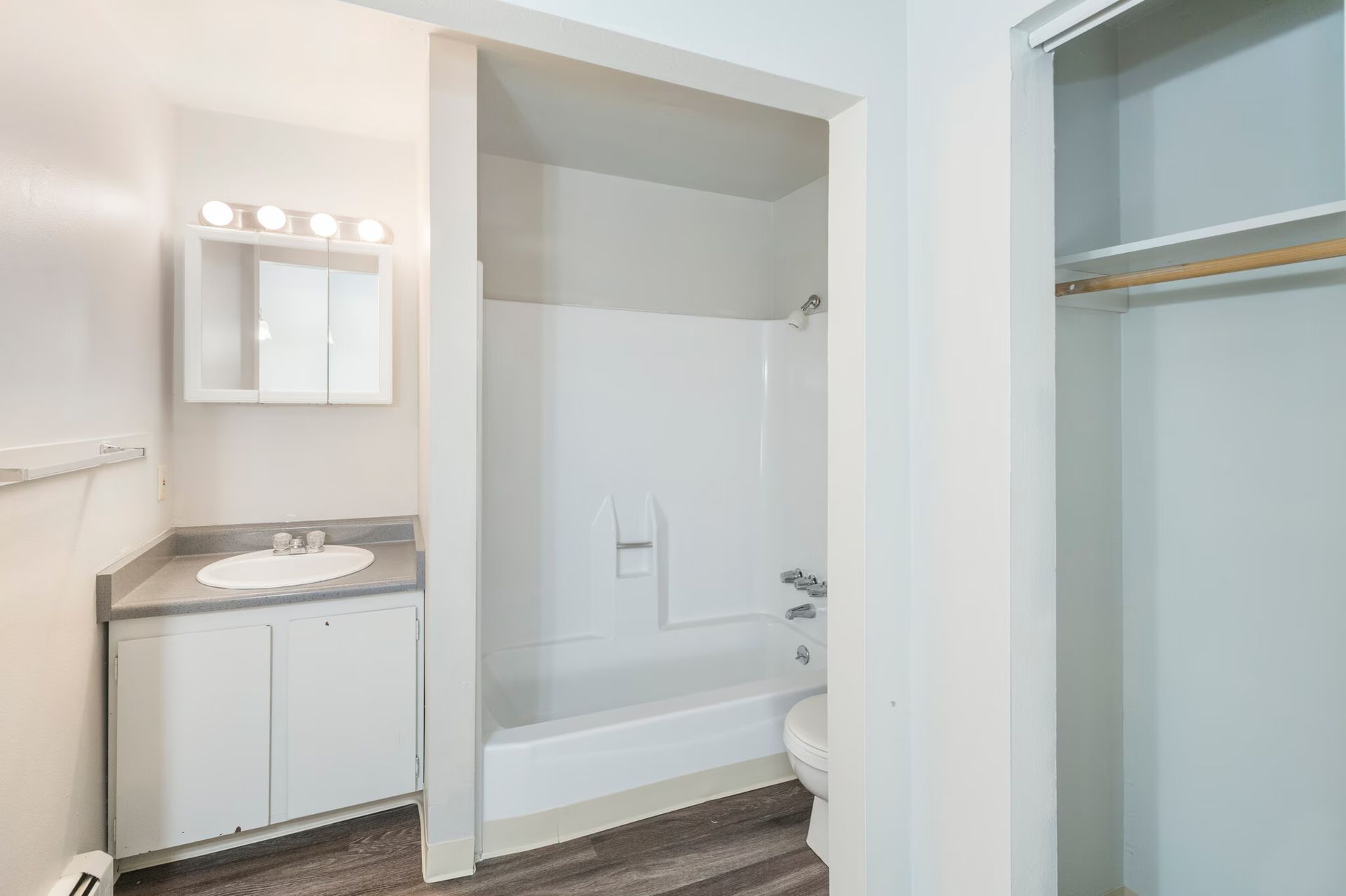 Bathroom with a white vanity, a tub/shower combo, and a closet.