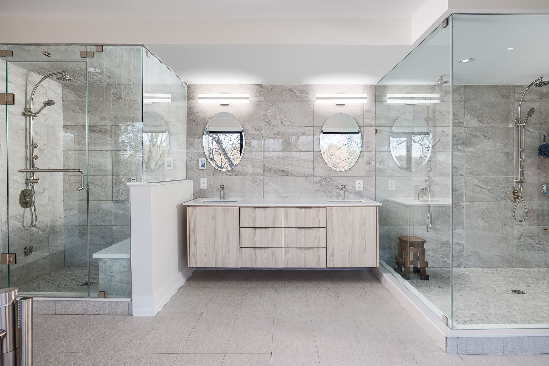 Modern bathroom with glass shower enclosures, double vanity, and marble finishes