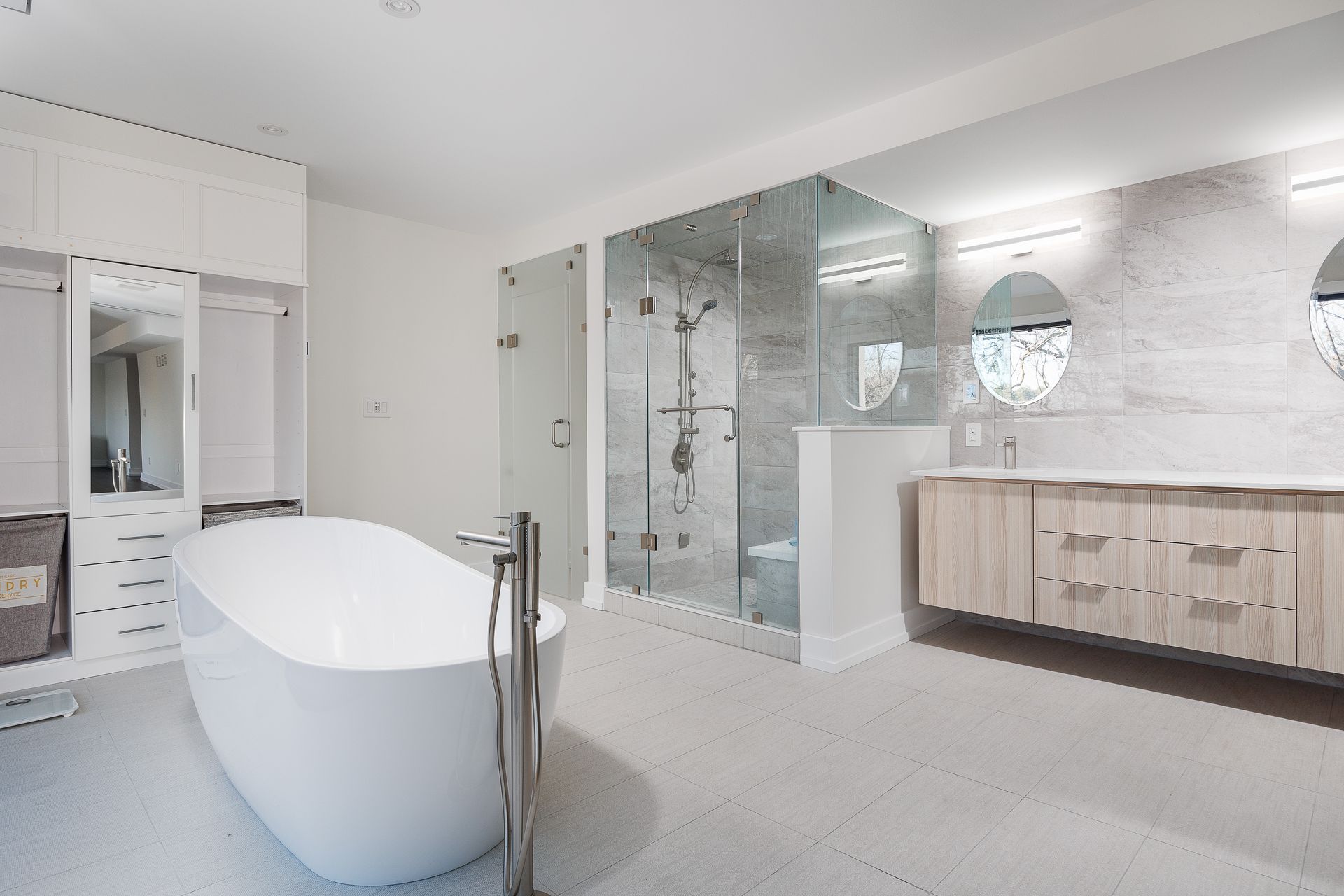 Modern bathroom with freestanding tub, glass shower, and vanity in white and wood tones