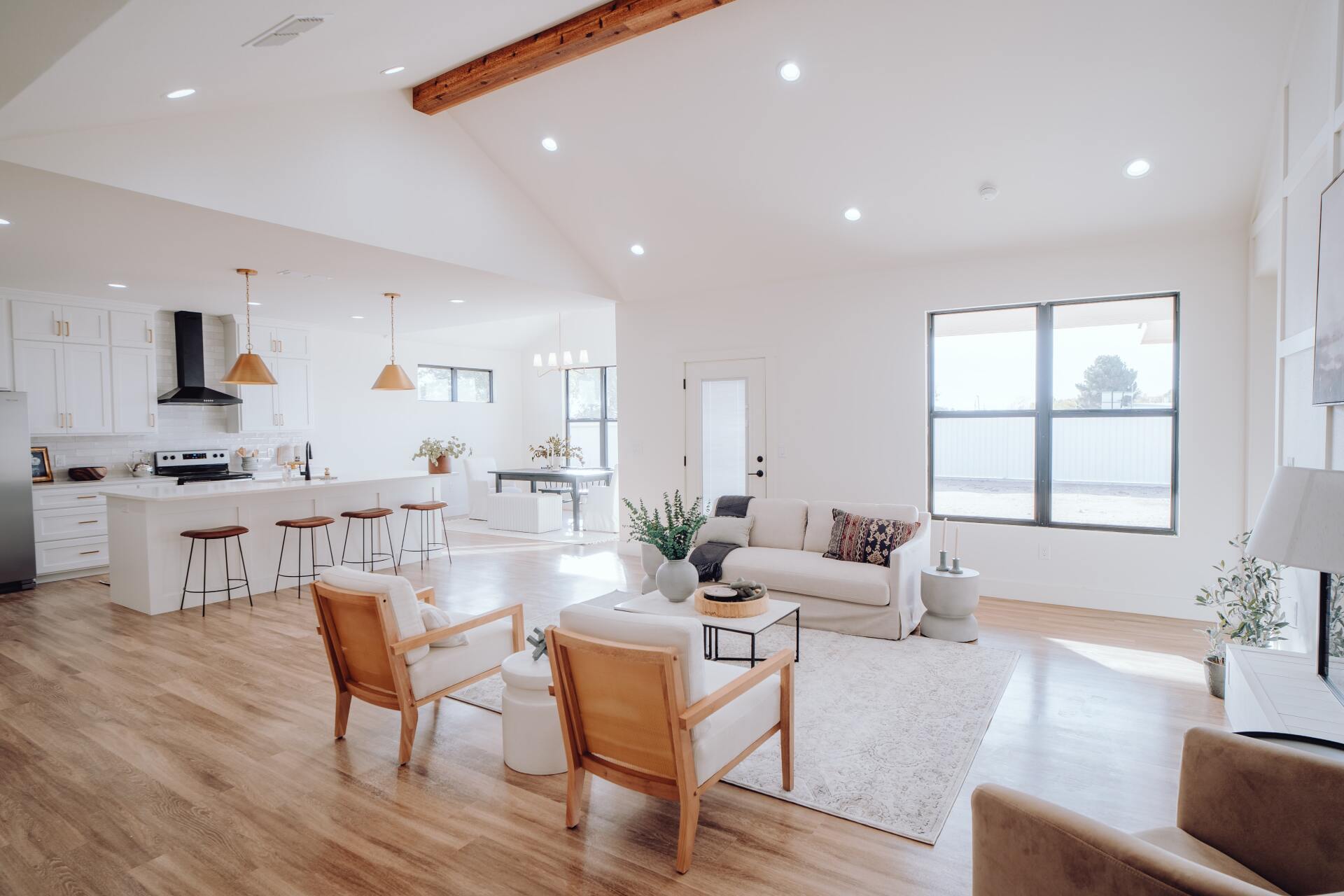 Bright, airy open-plan living room and kitchen with white walls, wood floors, and large windows