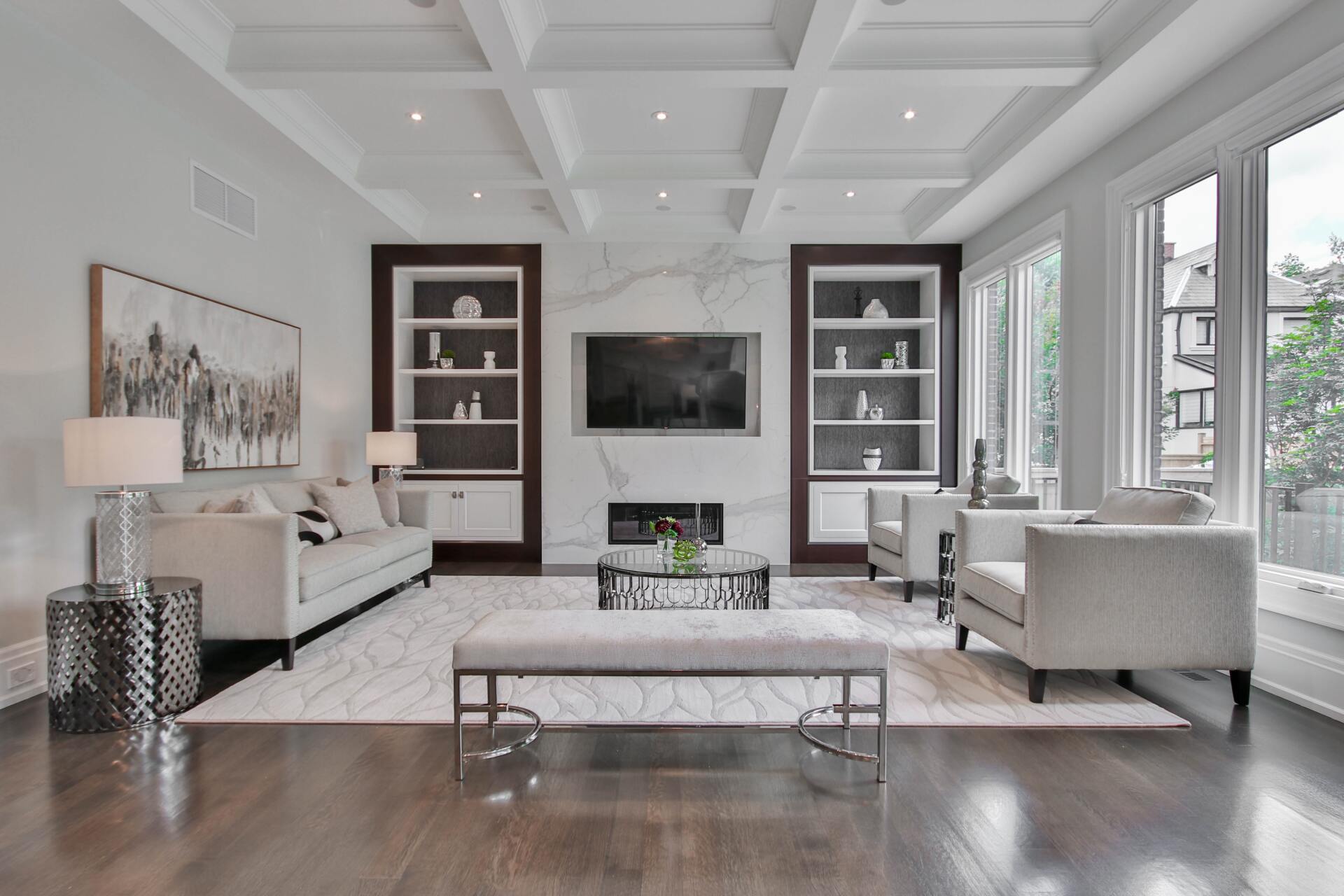 Modern living room with white sofas, dark wood floors, built-in shelves, and a wall-mounted TV