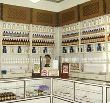 Interior de farmacia a la antigua usanza, con estantes blancos repletos de botellas y frascos detrás 