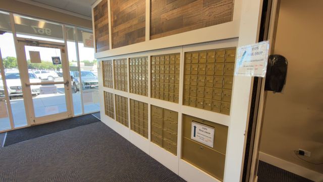 Lobby wall with rows of gold mailboxes beside a glass entry door