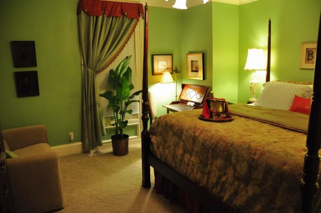 A bedroom with green walls and a four poster bed