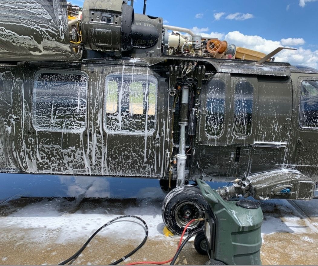 A military helicopter is being cleaned by a machine