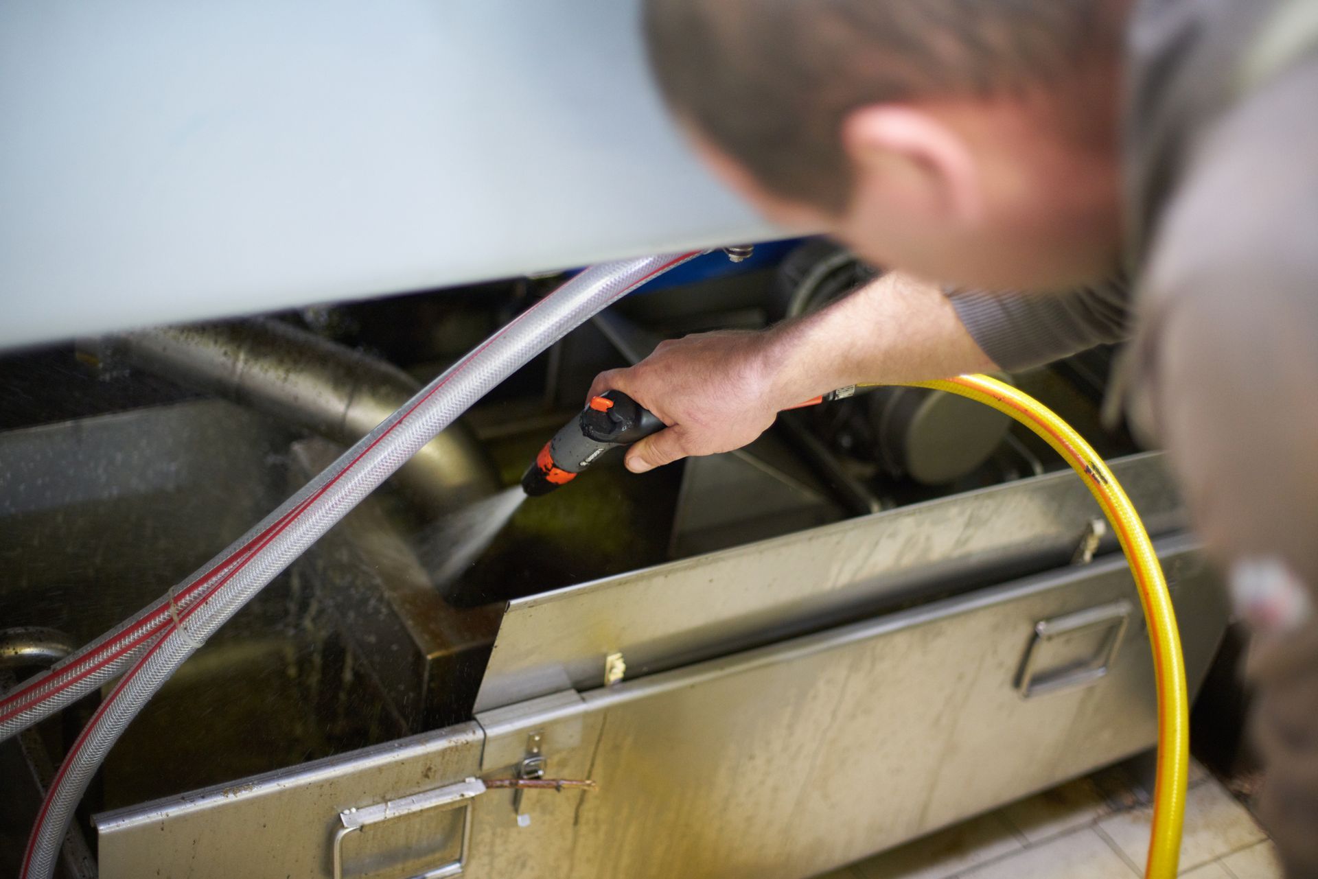 A man is cleaning a machine with a hose