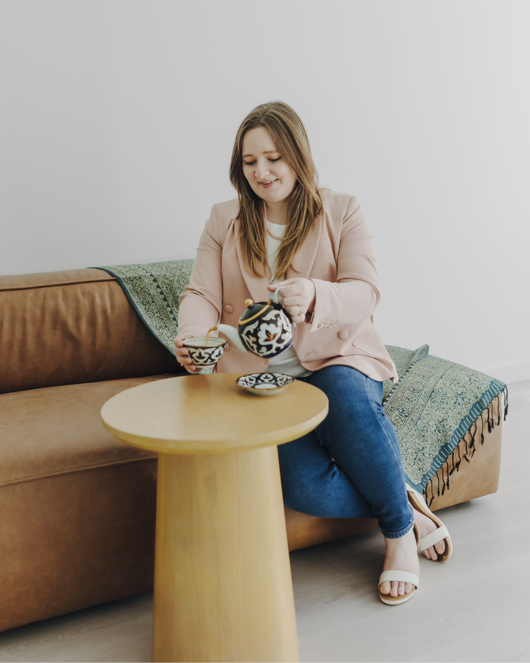 Woman arranging stacked patterned bowls on a small round table beside a sofa in a living room