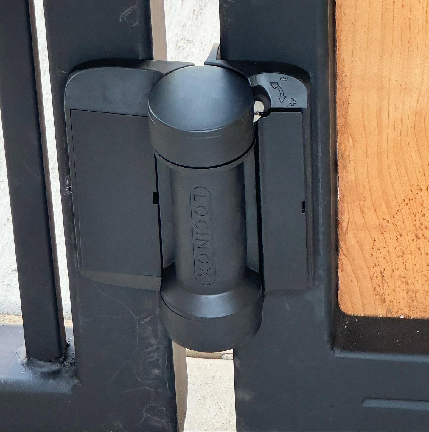 Close-up of a black door hinge on a wood-framed door