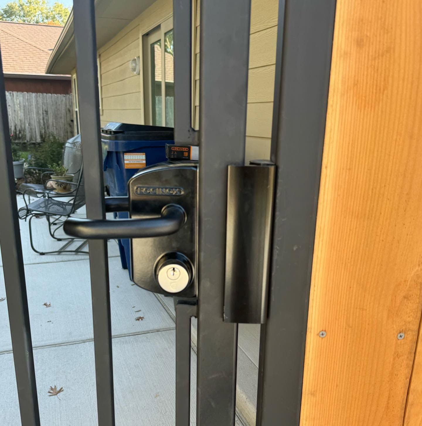 Close-up of a black door handle and lock on a glass patio door with a wooden frame