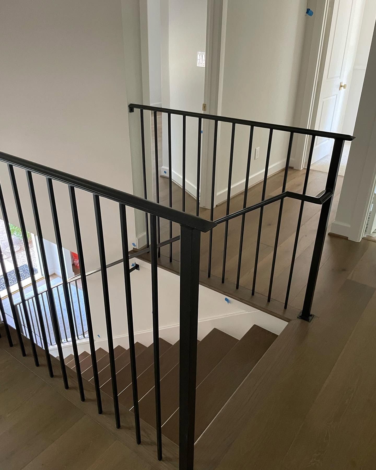 Black metal stair railing on a landing beside a carpeted staircase in a home hallway
