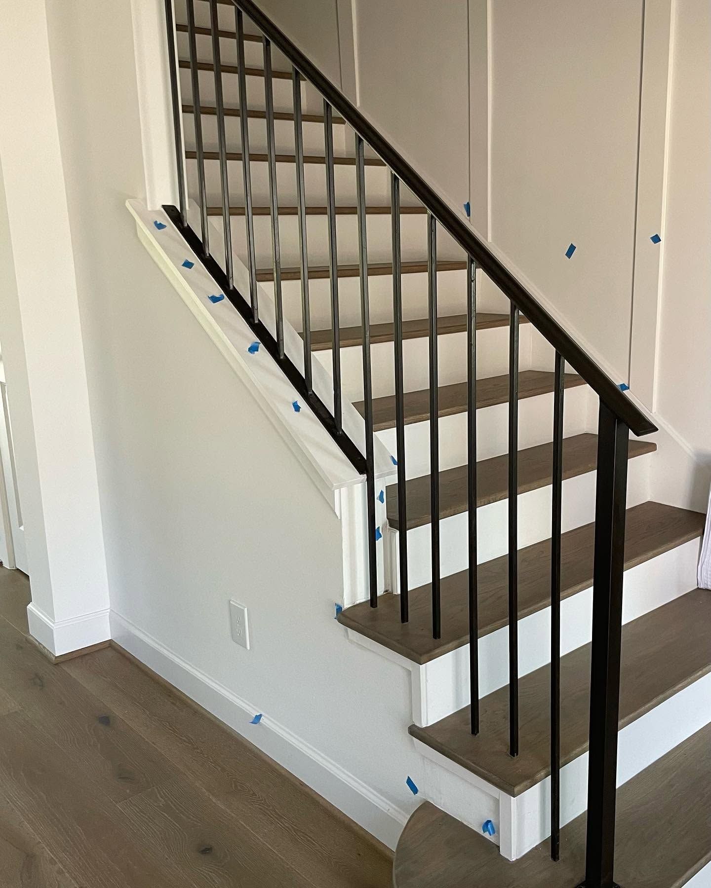 Interior staircase with white walls, dark railing, and carpeted steps in a hallway