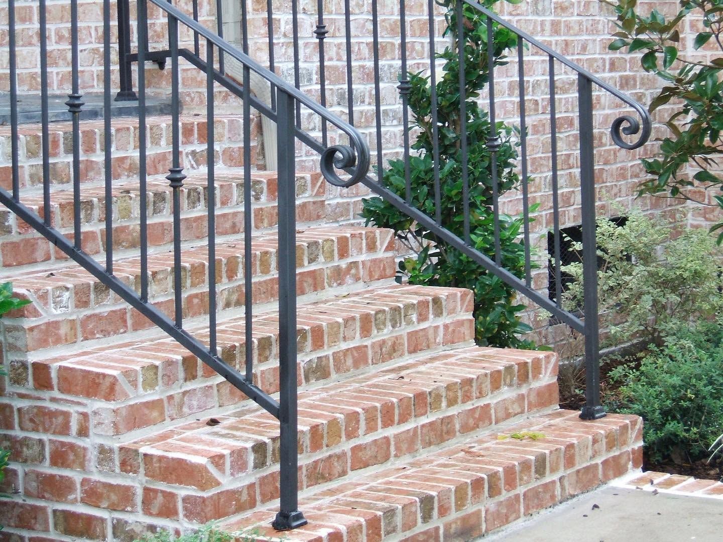 Brick outdoor staircase with black metal railing and brick wall backdrop