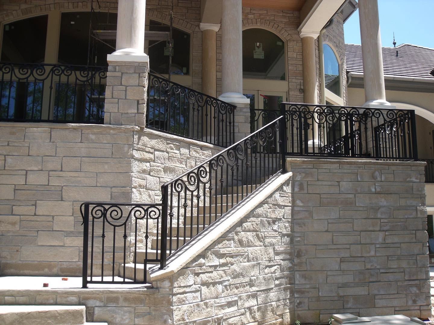 Stone staircase with black wrought-iron railings leading up to a building entrance
