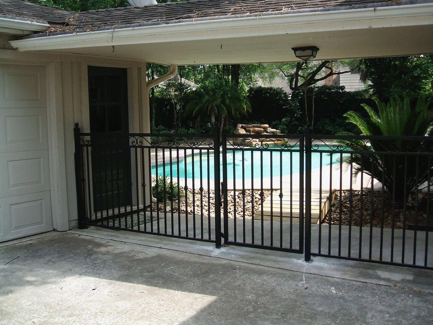 Covered patio with black gate overlooking a swimming pool and backyard greenery