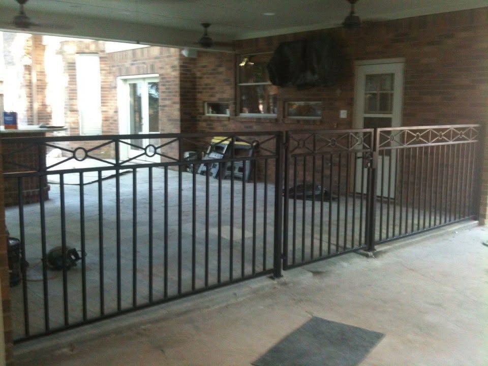 Covered brick patio with black metal railing and outdoor furniture.