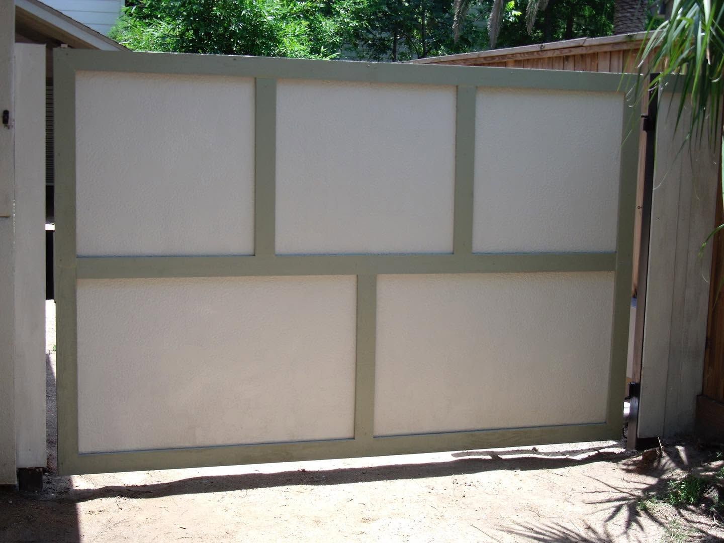 Closed beige sliding gate with four panels and a top frame, set in a driveway
