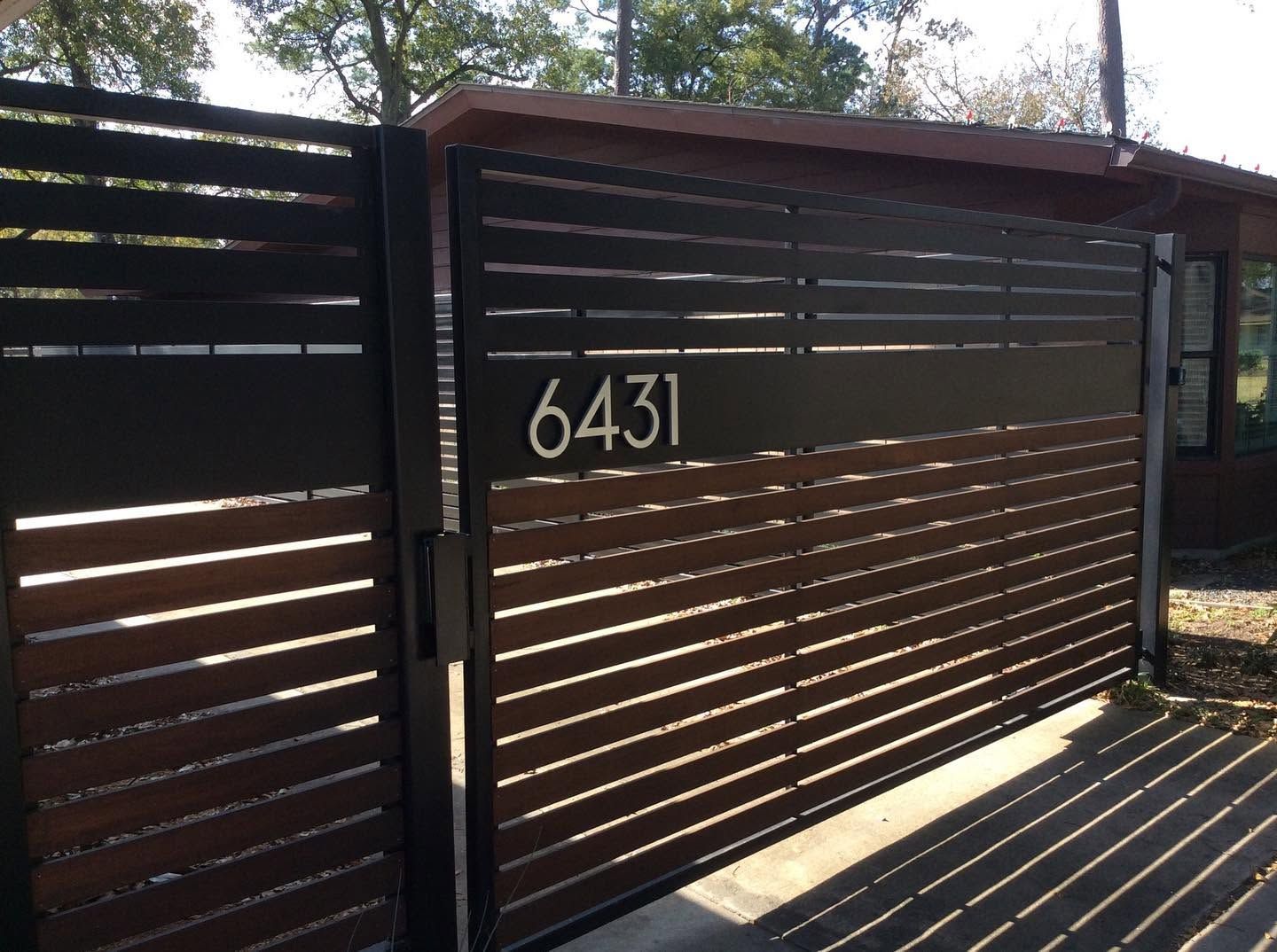 Modern slatted wooden gate with house number 6431 in sunlight