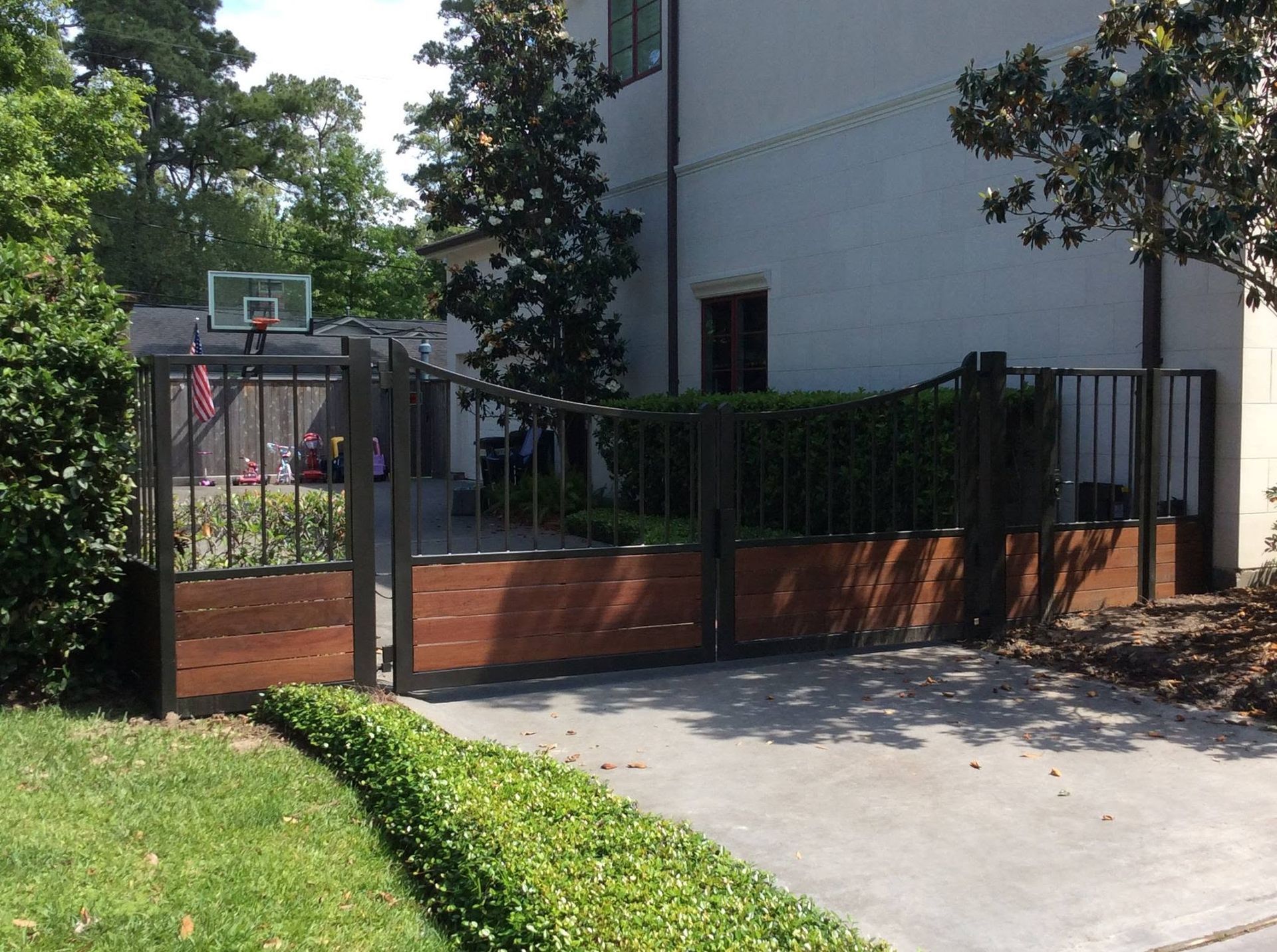 Backyard with basketball hoop, wooden fence, and driveway beside a house