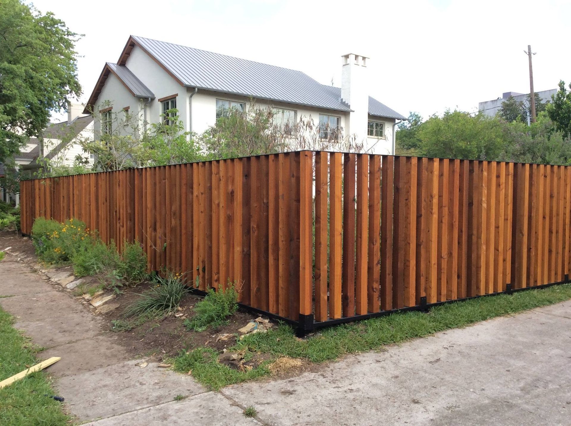 Wooden privacy fence around a corner lot beside a house and sidewalk