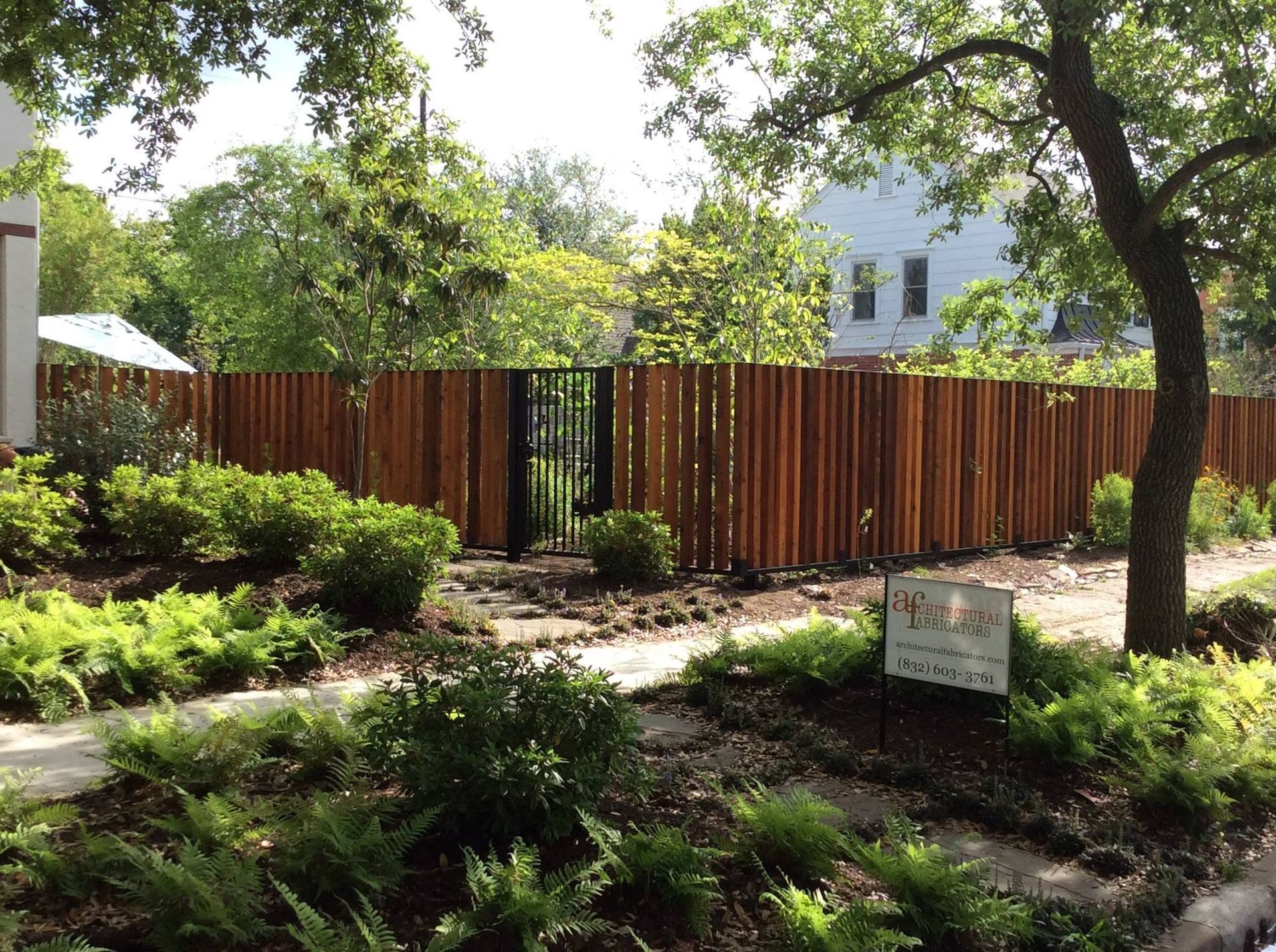 Garden with wooden fence, trees, and a small sign in a landscaped yard