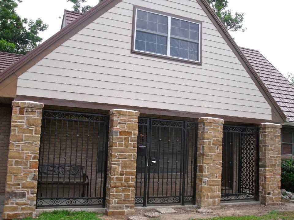 Brick house entrance with two black metal security doors and a small upper window under a gabled roof