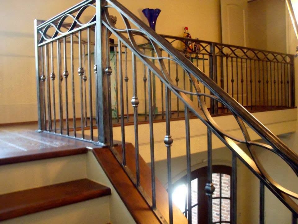 Wrought-iron stair railing with decorative circles beside a wooden staircase and warm interior walls