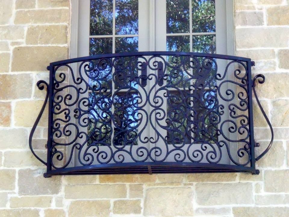 Ornate black wrought-iron balcony railing on a stone building facade