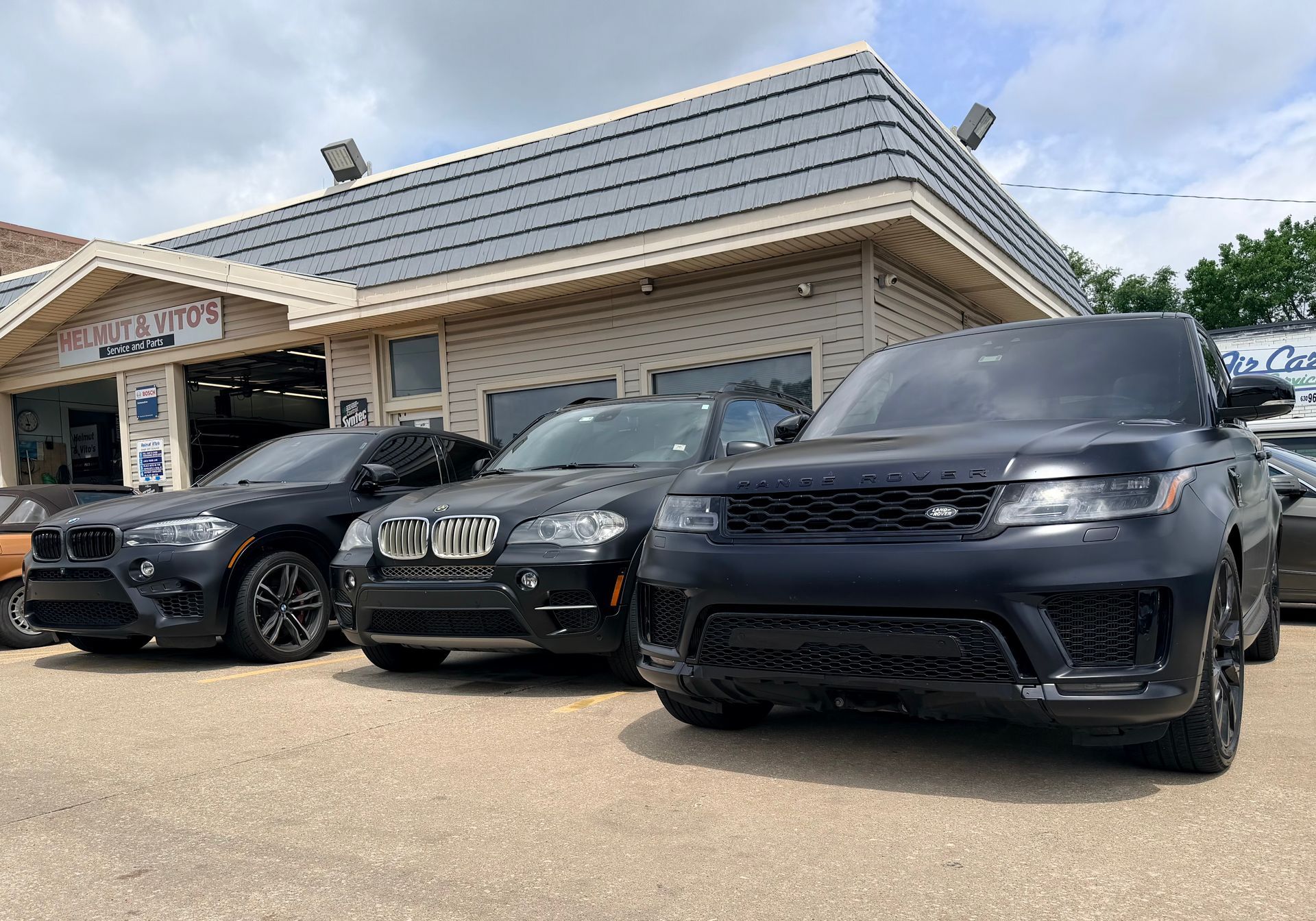 Three black BMW SUVs parked outside a dealership building.
