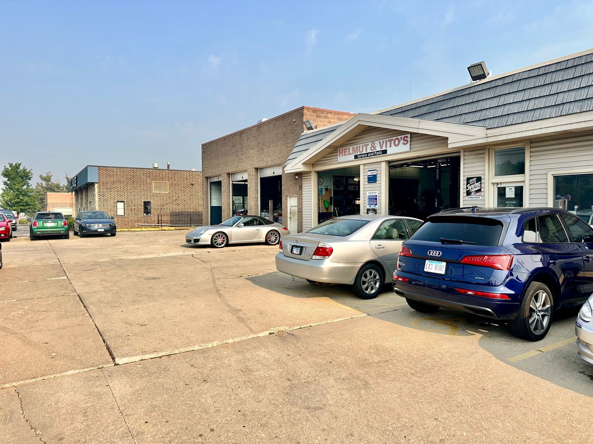 Parking lot outside a storefront with several parked cars on a sunny day