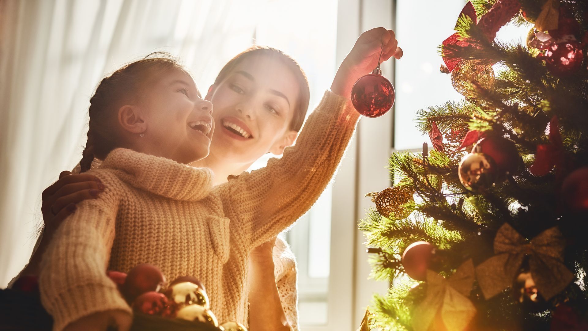 mother helping her daughter hang ornaments
