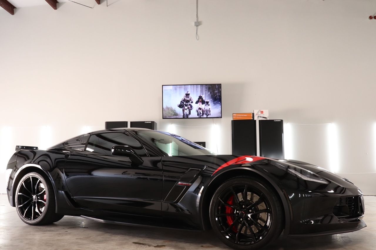 A black sports car is parked in a garage next to a television.
