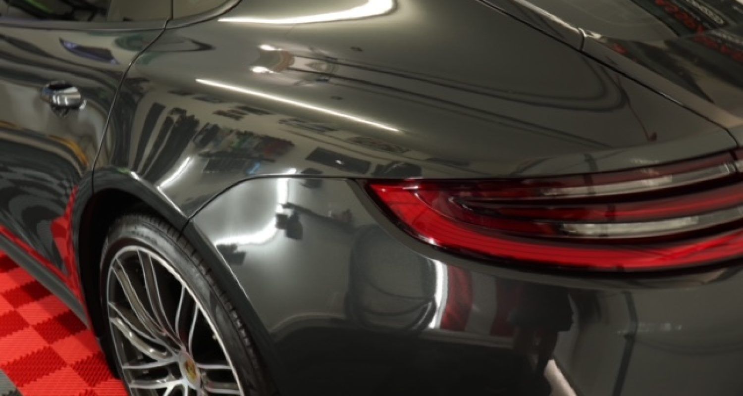 A black car is parked on a red tiled floor in a garage.