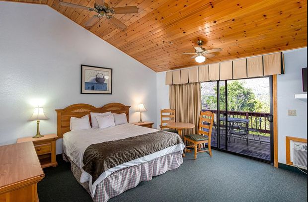 Bedroom with a queen bed, wooden ceiling, and balcony access.