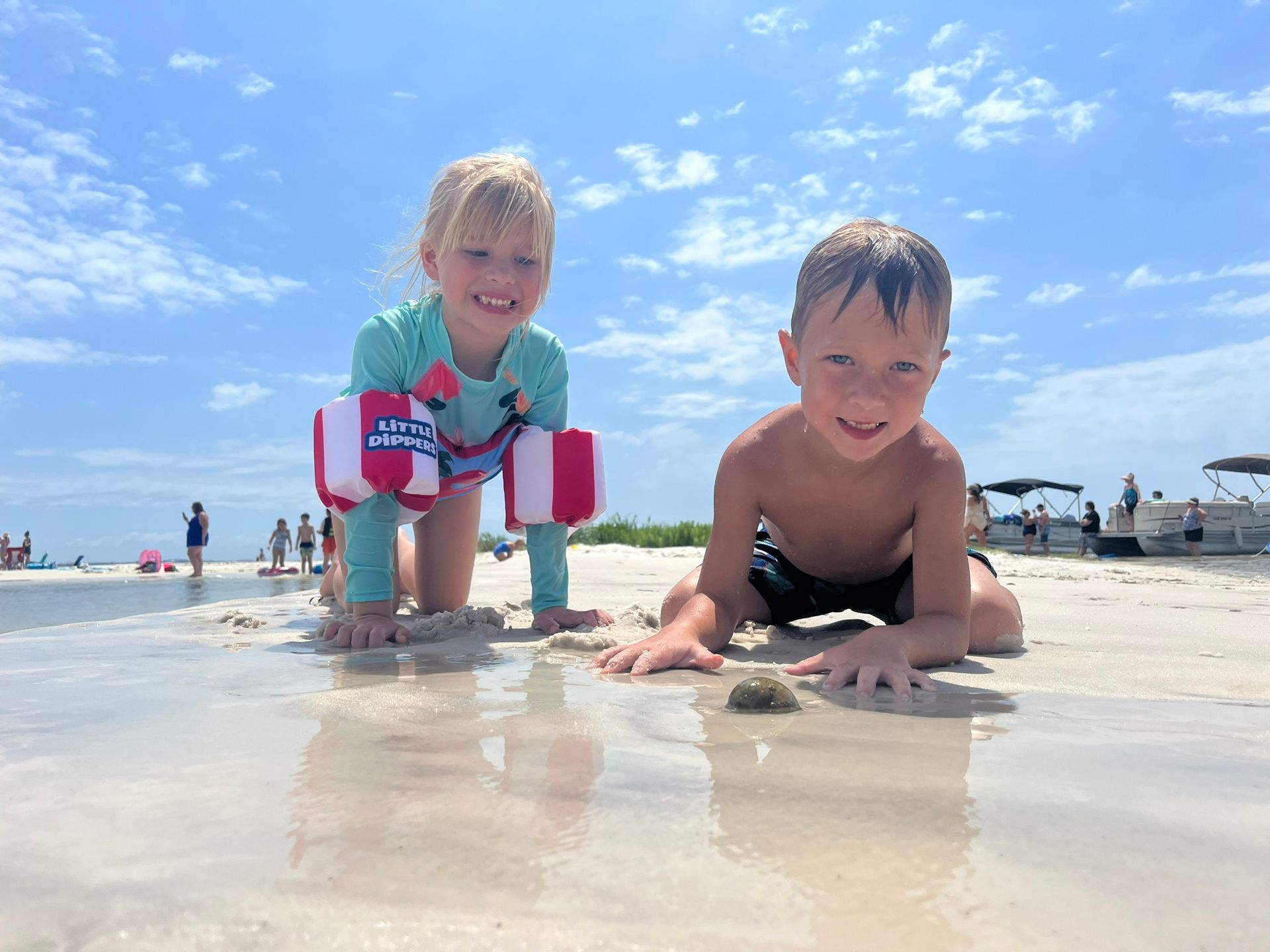 A boy and a girl are laying on the beach.