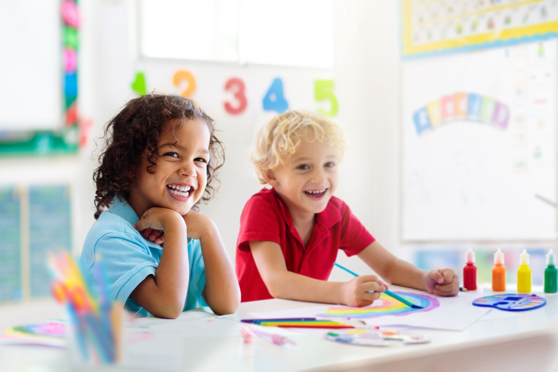 A boy and a girl are sitting at a table in a classroom.