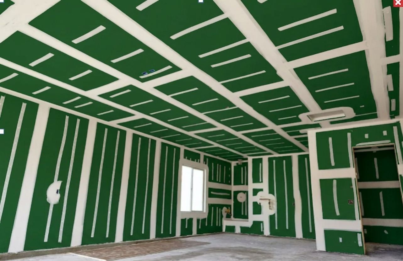 Unfinished room with green drywall, white ceiling strips, window, and built-in shelving.