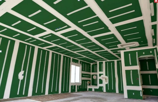 Unfinished room with green drywall, white ceiling strips, window, and built-in shelving.