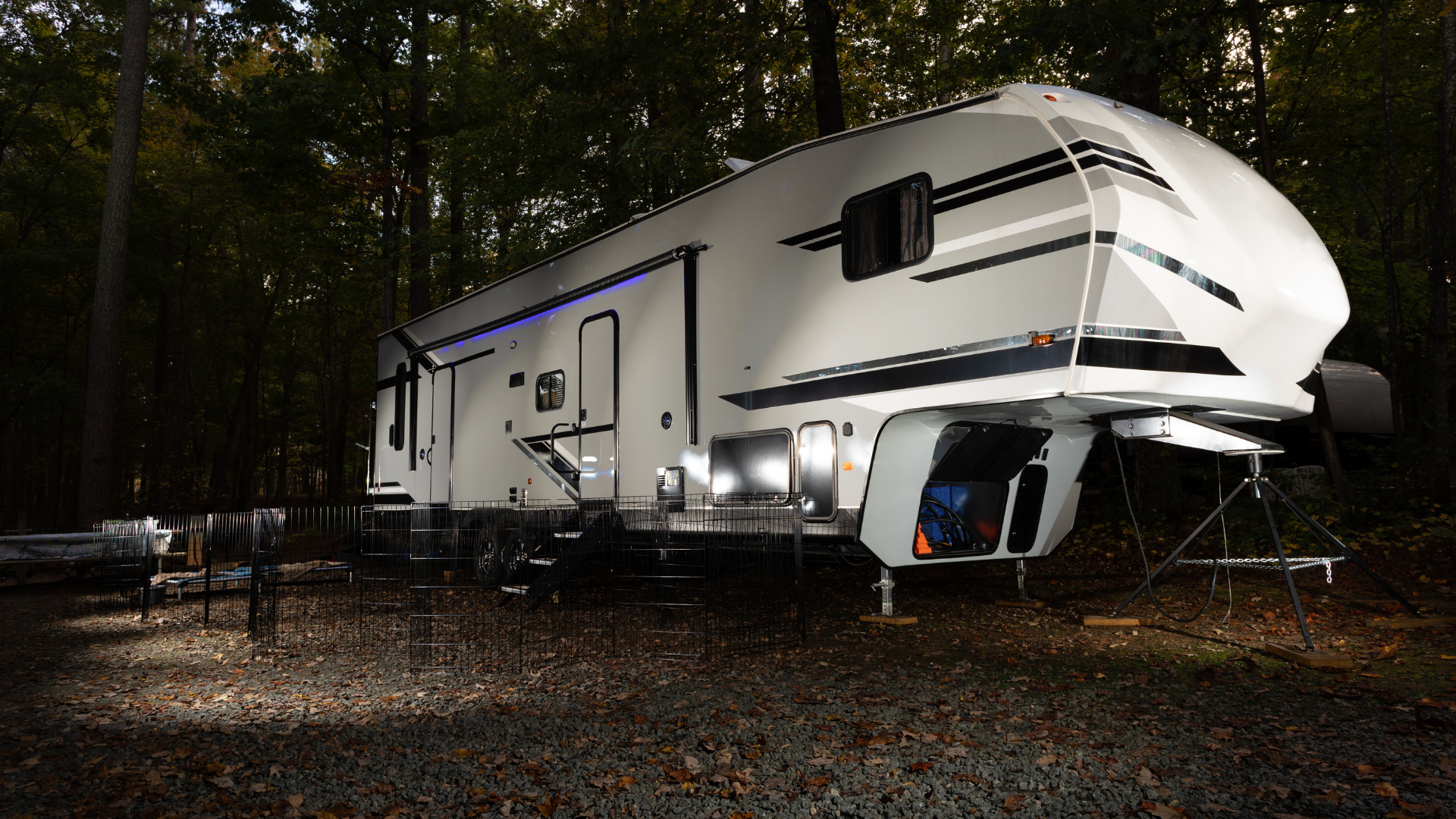 A white rv is parked in the woods at night