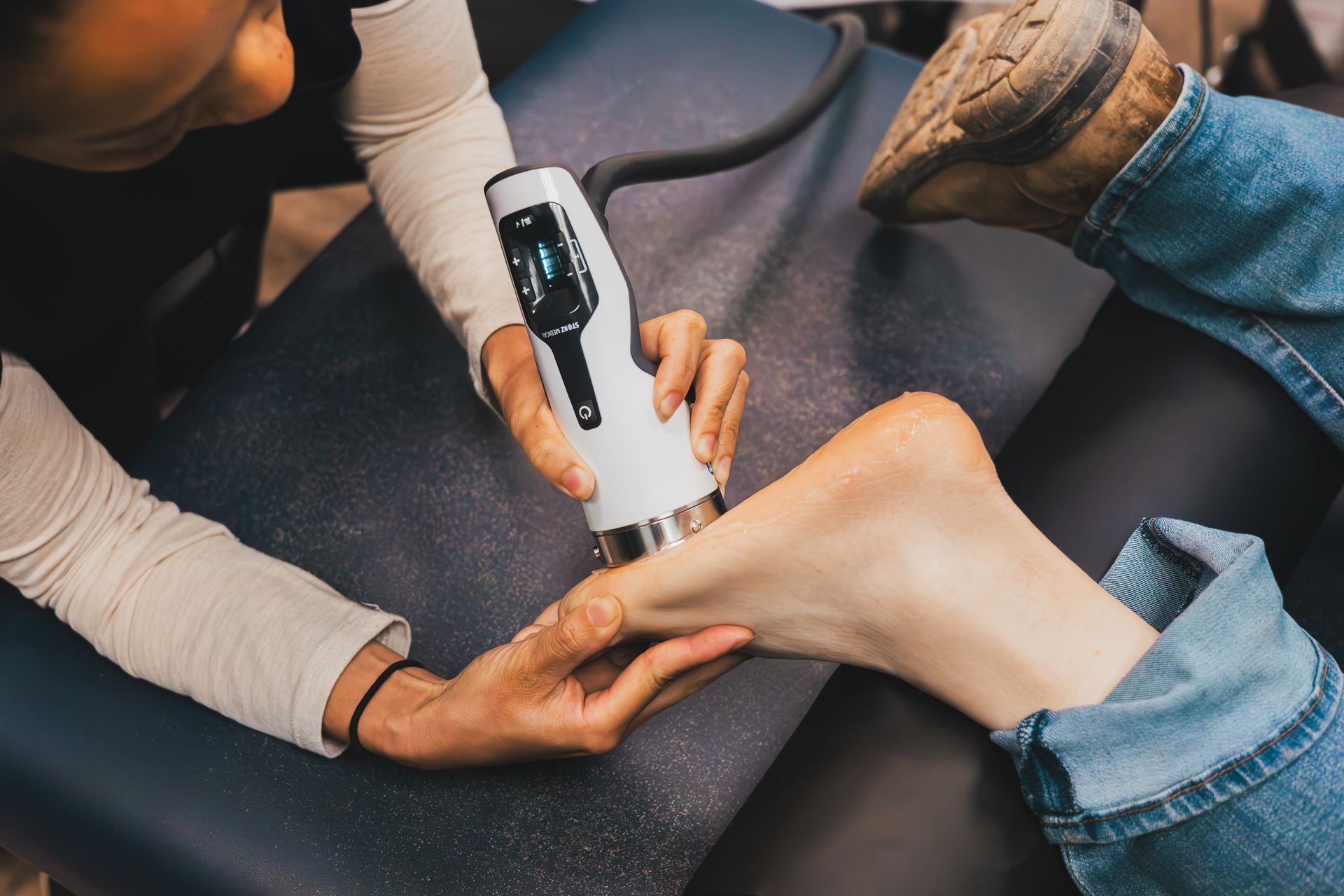 Therapist using ultrasound device on patient's foot in a clinical setting.