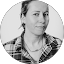 Woman with light skin, wearing a plaid shirt, looking towards the camera, in a gray-scale photo.