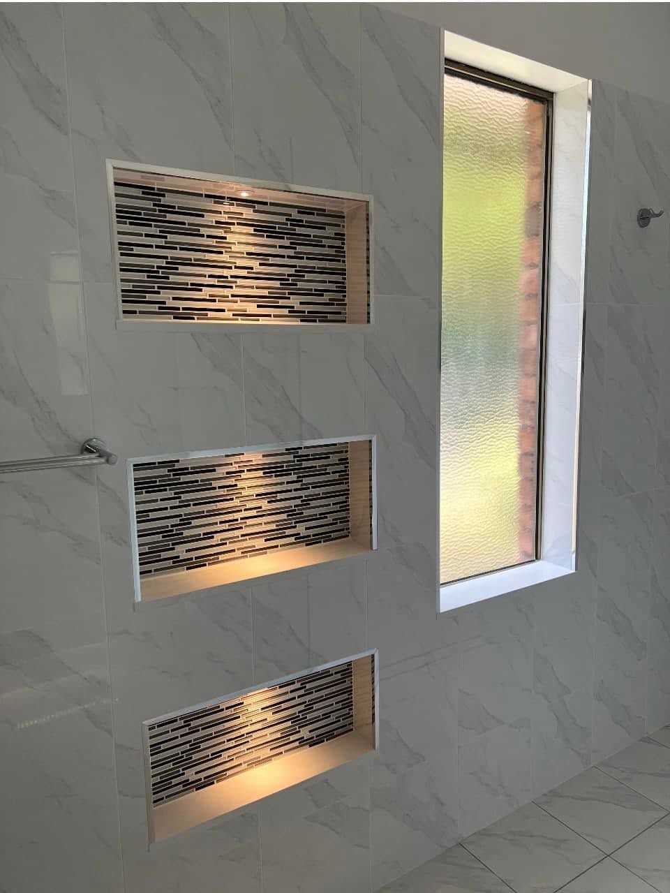 Modern interior wall with three lit rectangular niches and a tall frosted glass window panel
