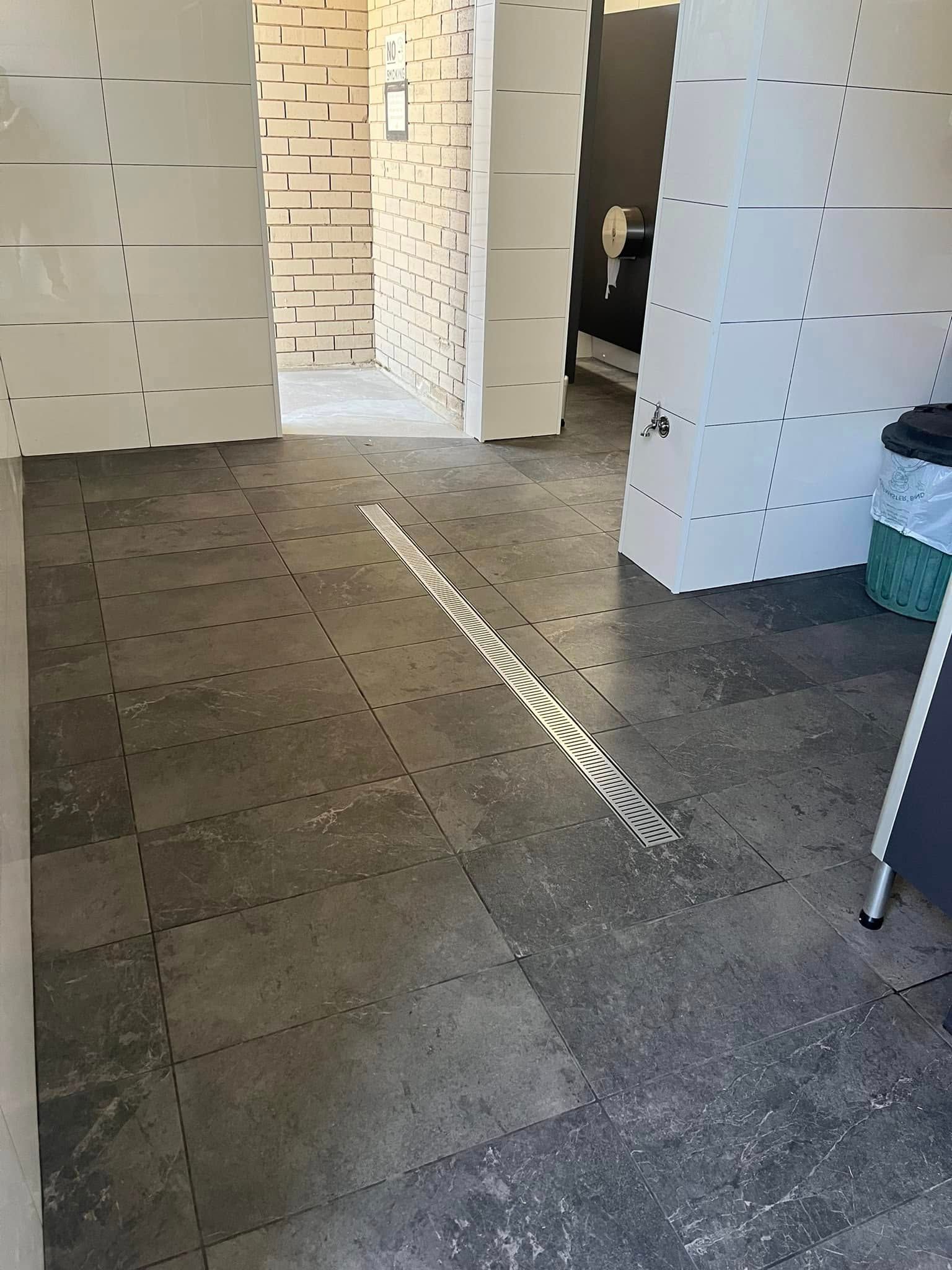 Interior under construction with tiled floor, white walls, and a doorway to a brick-lined room.