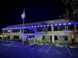 Night view of a lit two-story office building with an American flag and empty parking lot