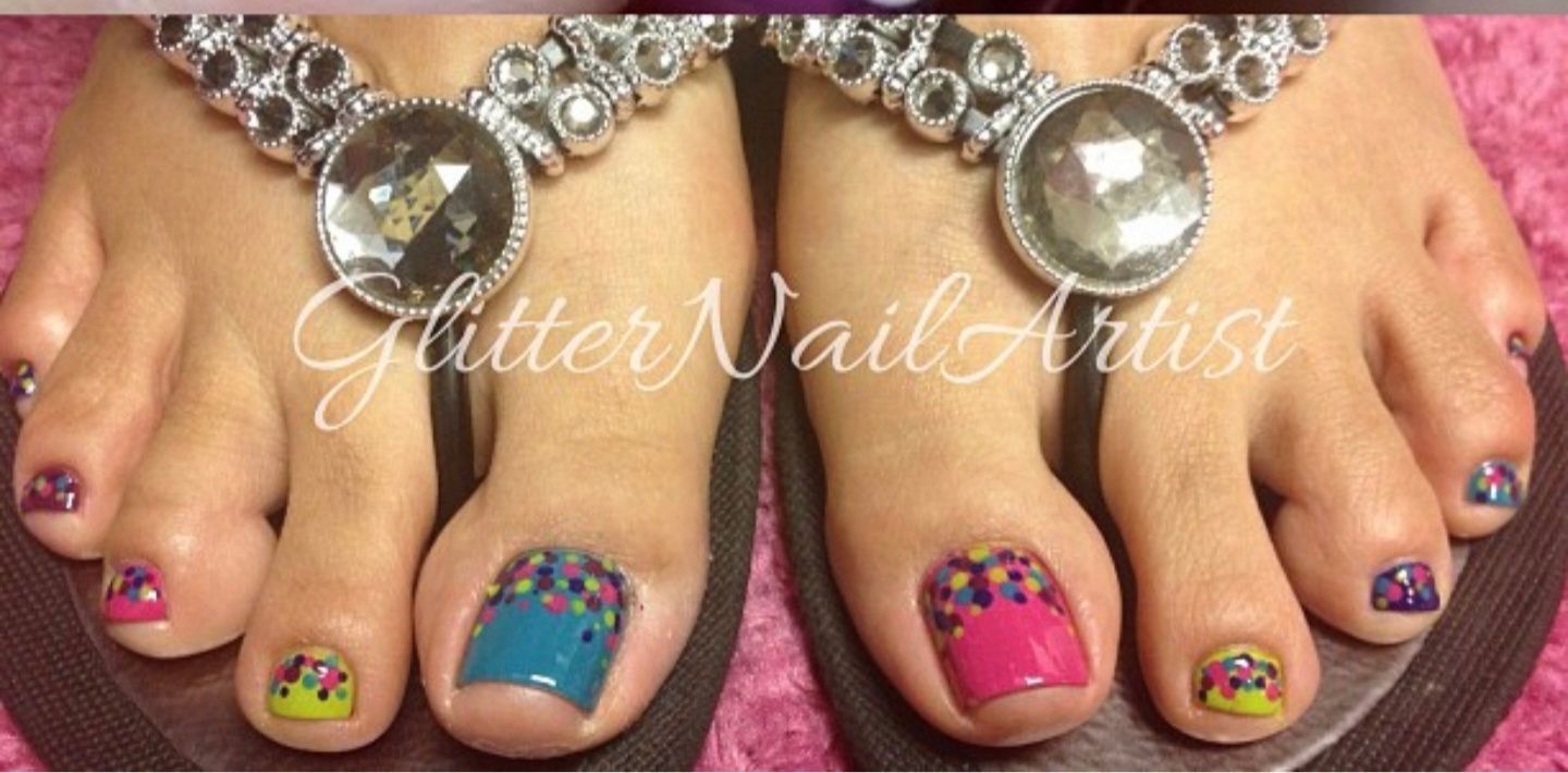 Manicured hands with black, red glitter, and white leopard-print nail art on a gray surface