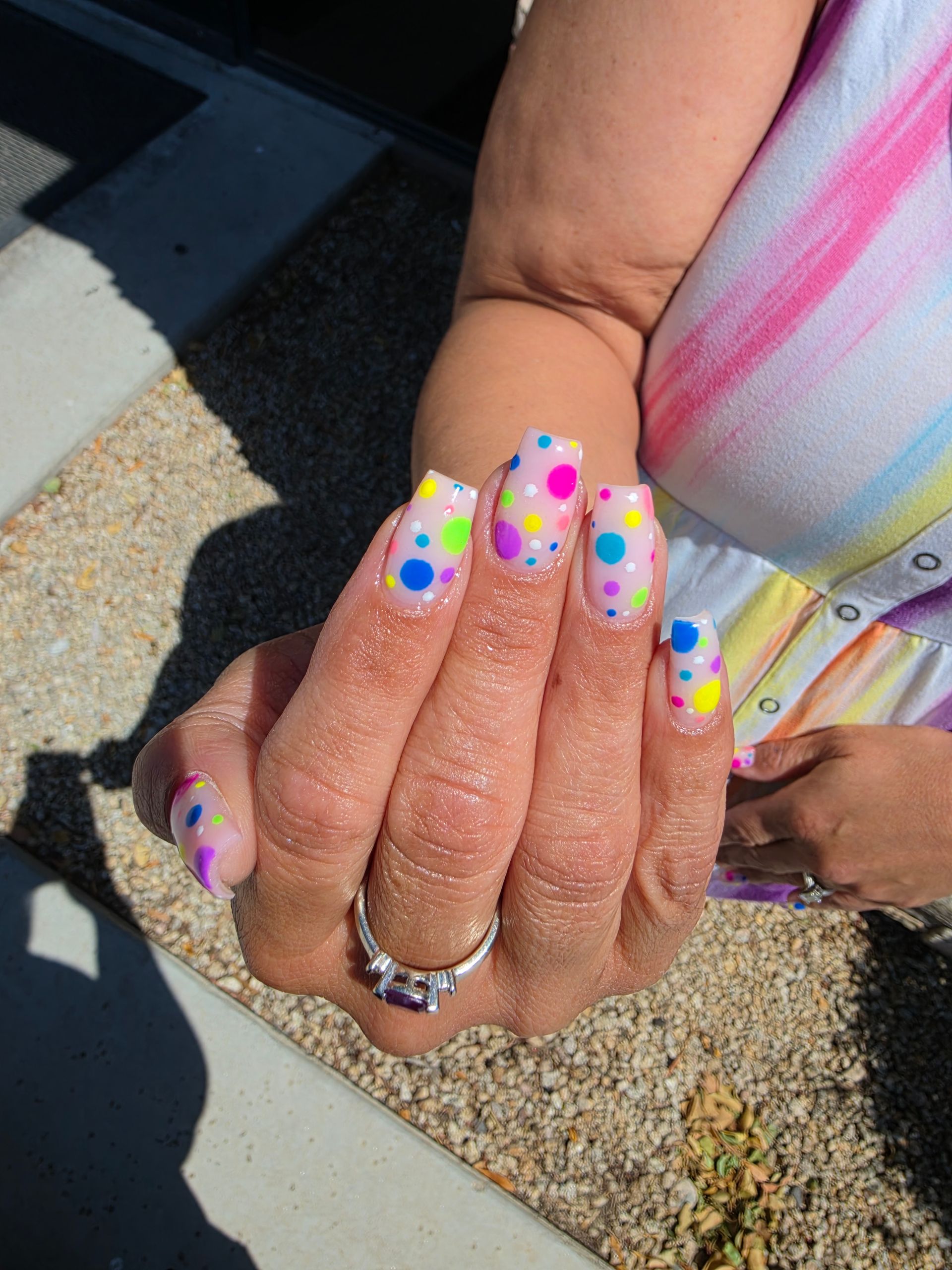 Hands with colorful smiley-face nail art and blue checkered accents.