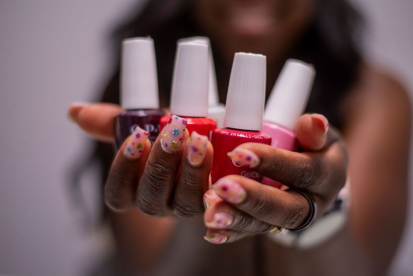 Hands with pink-and-white floral French-tip nails resting on a white surface