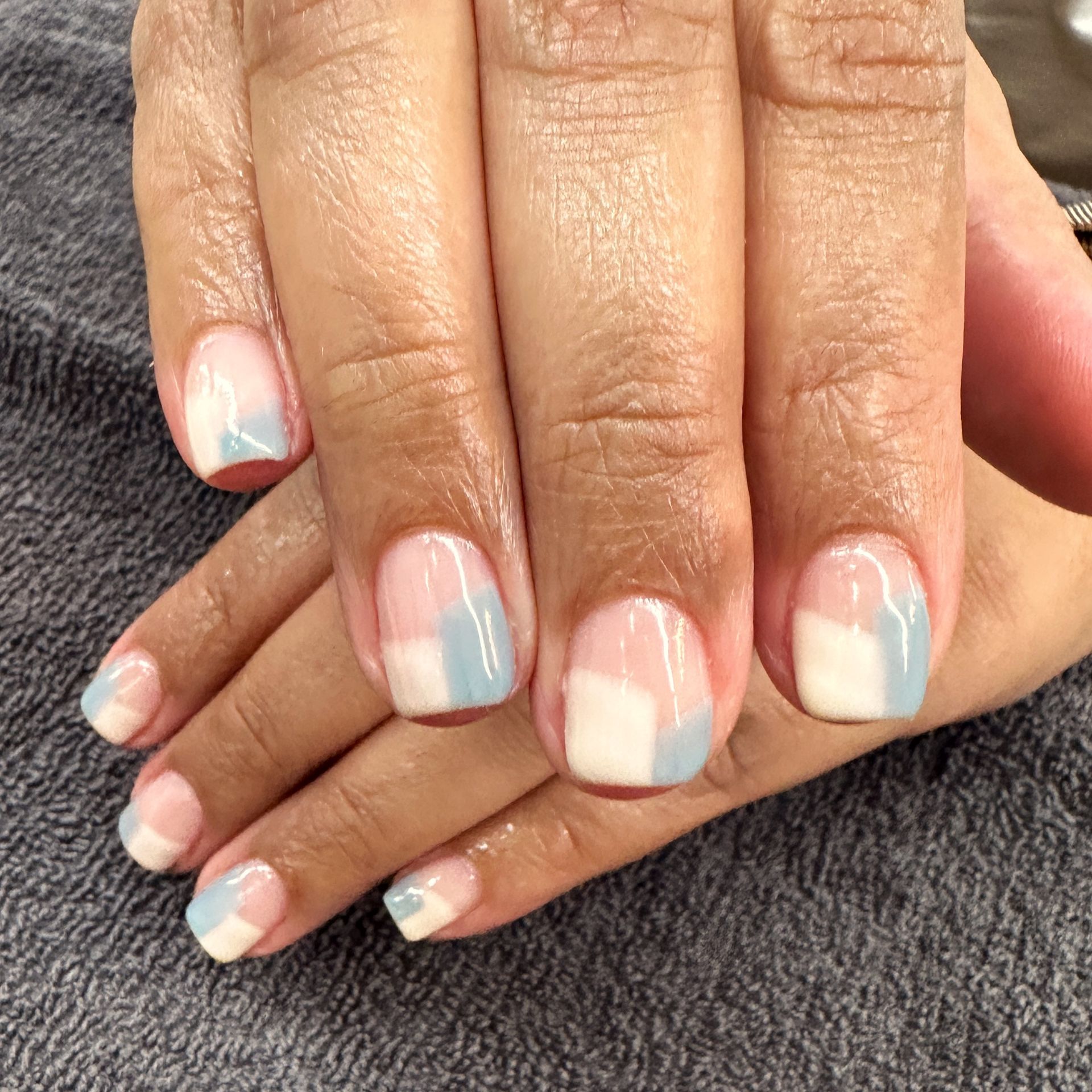 Pastel pink and blue gradient manicure on neatly shaped fingernails, shown close-up on two hands